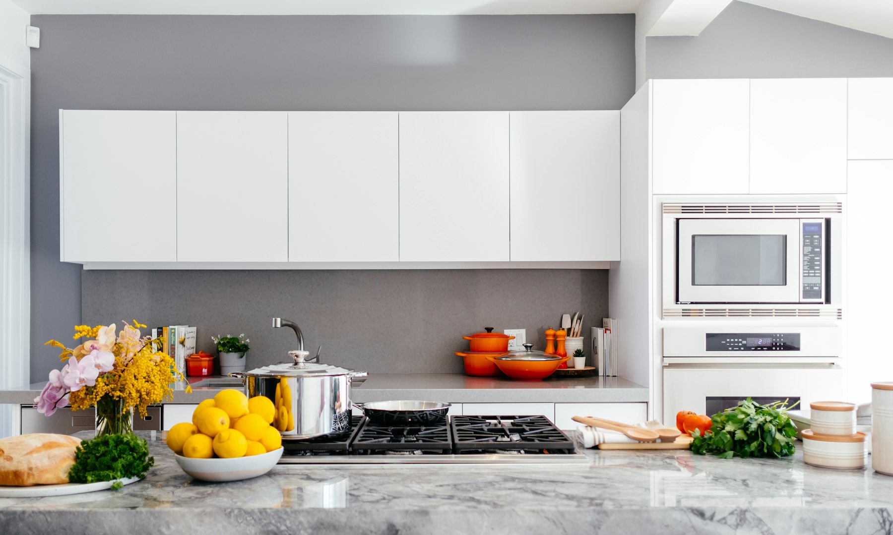 A bright home kitchen with a bowl of lemons, fresh herbs, and pots on the stove